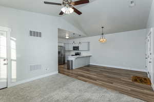 Kitchen with stainless steel appliances, a kitchen bar, dark hardwood / wood-style floors, lofted ceiling, and pendant lighting