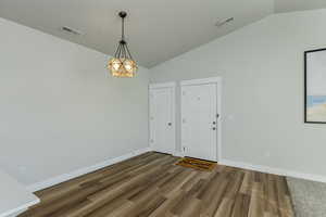 Empty room with dark wood-type flooring and lofted ceiling