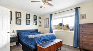 Bedroom with ceiling fan, a textured ceiling, and dark colored carpet