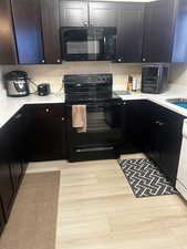 Kitchen with sink, black appliances, and light hardwood / wood-style floors