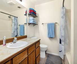 Full bathroom featuring shower / bath combo, vanity, hardwood / wood-style flooring, and toilet