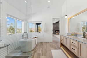 Bathroom featuring vanity, a large fireplace, lofted ceiling, and independent shower and bath