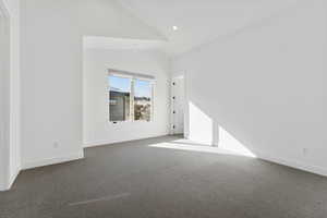 Unfurnished living room featuring dark colored carpet and lofted ceiling