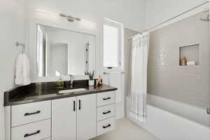 Bathroom with tile patterned floors, shower / bath combo with shower curtain, and vanity