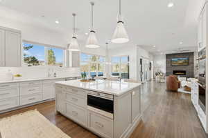 Kitchen with hardwood / wood-style flooring, decorative light fixtures, a large fireplace, and white cabinets