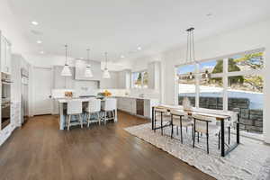 Kitchen with stainless steel appliances, hanging light fixtures, dark wood-type flooring, backsplash, and a spacious island