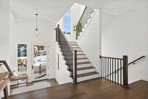 Stairs featuring hardwood / wood-style flooring, a towering ceiling, and a wealth of natural light