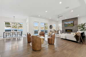 Living room with a large fireplace, hardwood / wood-style floors, and ceiling fan with notable chandelier