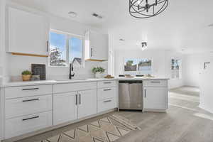 Kitchen featuring stainless steel dishwasher, plenty of natural light, sink, and light hardwood / wood-style flooring