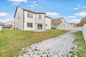 Rear view of house with central AC unit, a patio area, and a lawn