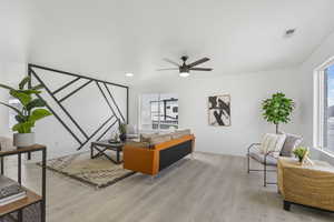 Living room featuring ceiling fan, a healthy amount of sunlight, and light hardwood / wood-style floors