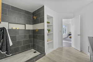 Bathroom with a tile shower, built in features, and wood-type flooring