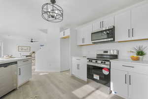 Kitchen featuring white cabinetry, light hardwood / wood-style flooring, pendant lighting, and appliances with stainless steel finishes