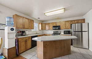 Kitchen featuring light tile patterned flooring, sink, a kitchen island, and black appliances