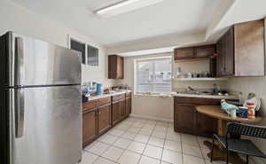 Kitchen with light tile patterned floors and stainless steel refrigerator