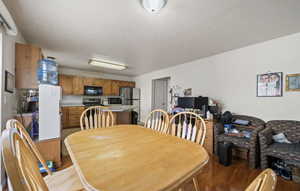 Dining space with a textured ceiling and light hardwood / wood-style flooring