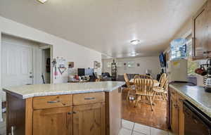 Kitchen featuring a center island, dishwasher, light tile patterned flooring, and a textured ceiling