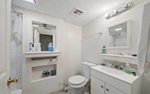 Bathroom with a tile shower, vanity, and toilet