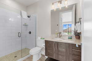 Bathroom with tile patterned floors, vanity, toilet, and walk in shower