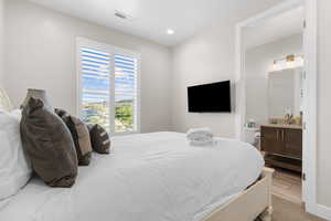 Bedroom with ensuite bathroom, sink, and light wood-type flooring