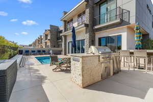 View of pool with a bar, an outdoor kitchen, grilling area, and a patio area