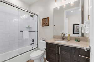 Full bathroom with vanity, toilet, and bath / shower combo with glass door