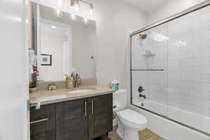 Full bathroom featuring vanity, toilet, enclosed tub / shower combo, and wood-type flooring