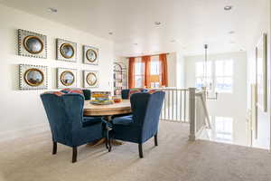 Dining room featuring light colored carpet, an inviting chandelier, and a wealth of natural light