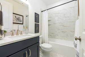 Full bathroom featuring shower / bath combination with curtain, vanity, and toilet