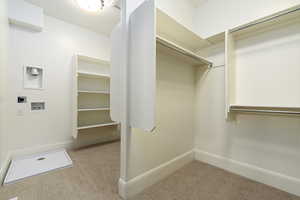 Walk in closet featuring light colored carpet