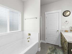 Bathroom with vanity, tile patterned flooring, and a bathtub