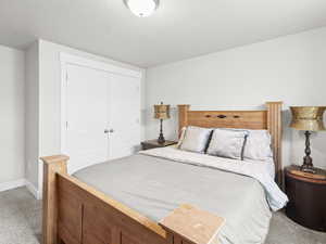 Bedroom with a textured ceiling, carpet floors, and a closet