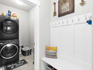 Laundry area with light tile patterned flooring and stacked washer / drying machine