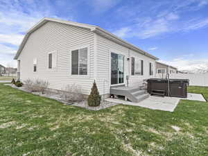 Back of house with a yard, a patio, and a hot tub