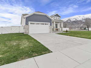 View of front of home featuring a mountain view, a front yard, and a garage