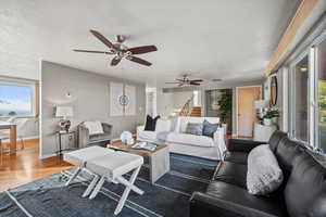 Living room featuring ceiling fan, hardwood / wood-style floors, and a textured ceiling