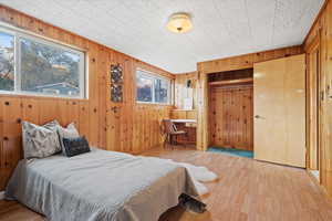 Bedroom with light hardwood / wood-style flooring, a closet, and wood walls