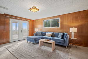 Carpeted living room featuring french doors and wood walls