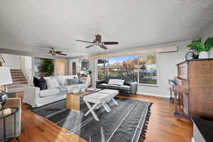 Living room with ceiling fan, wood-type flooring, and a textured ceiling