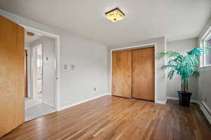 Unfurnished bedroom with hardwood / wood-style flooring, a closet, and a baseboard heating unit