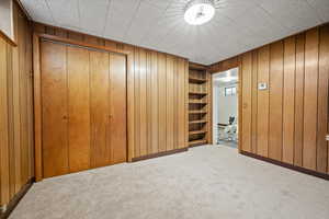 Unfurnished bedroom with carpet flooring, a closet, and wood walls