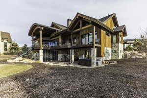 Rear view of property featuring a balcony, a hot tub, cooling unit, and a patio area