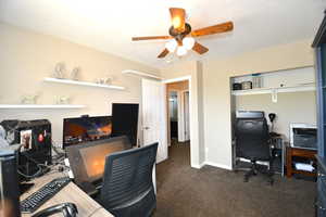 Home office with dark colored carpet and ceiling fan