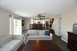 Carpeted living room with ceiling fan