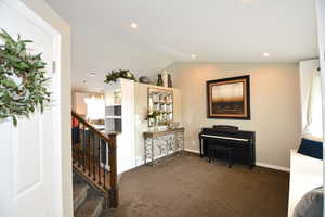 Interior space with dark carpet and vaulted ceiling