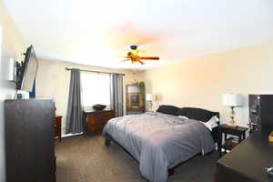 Bedroom featuring ceiling fan and dark carpet