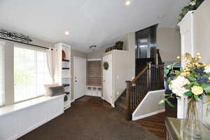 Foyer entrance featuring dark hardwood / wood-style flooring and vaulted ceiling