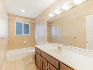 Full bathroom featuring tile patterned floors, toilet, vanity, and tiled shower / bath