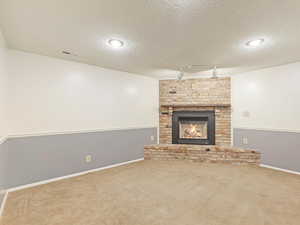 Unfurnished living room with a textured ceiling, carpet, and track lighting