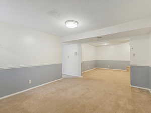 Basement with a textured ceiling and light carpet